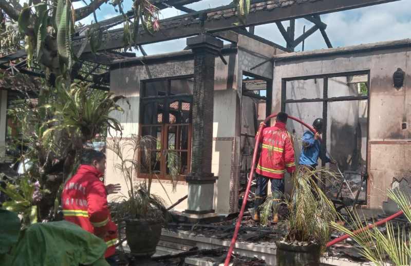 HANGUS TERBAKAR : Petugas menyemprotkan air ke bangunan bale dauh yang terbakar, Rabu (20/3/2024).(Istimewa)