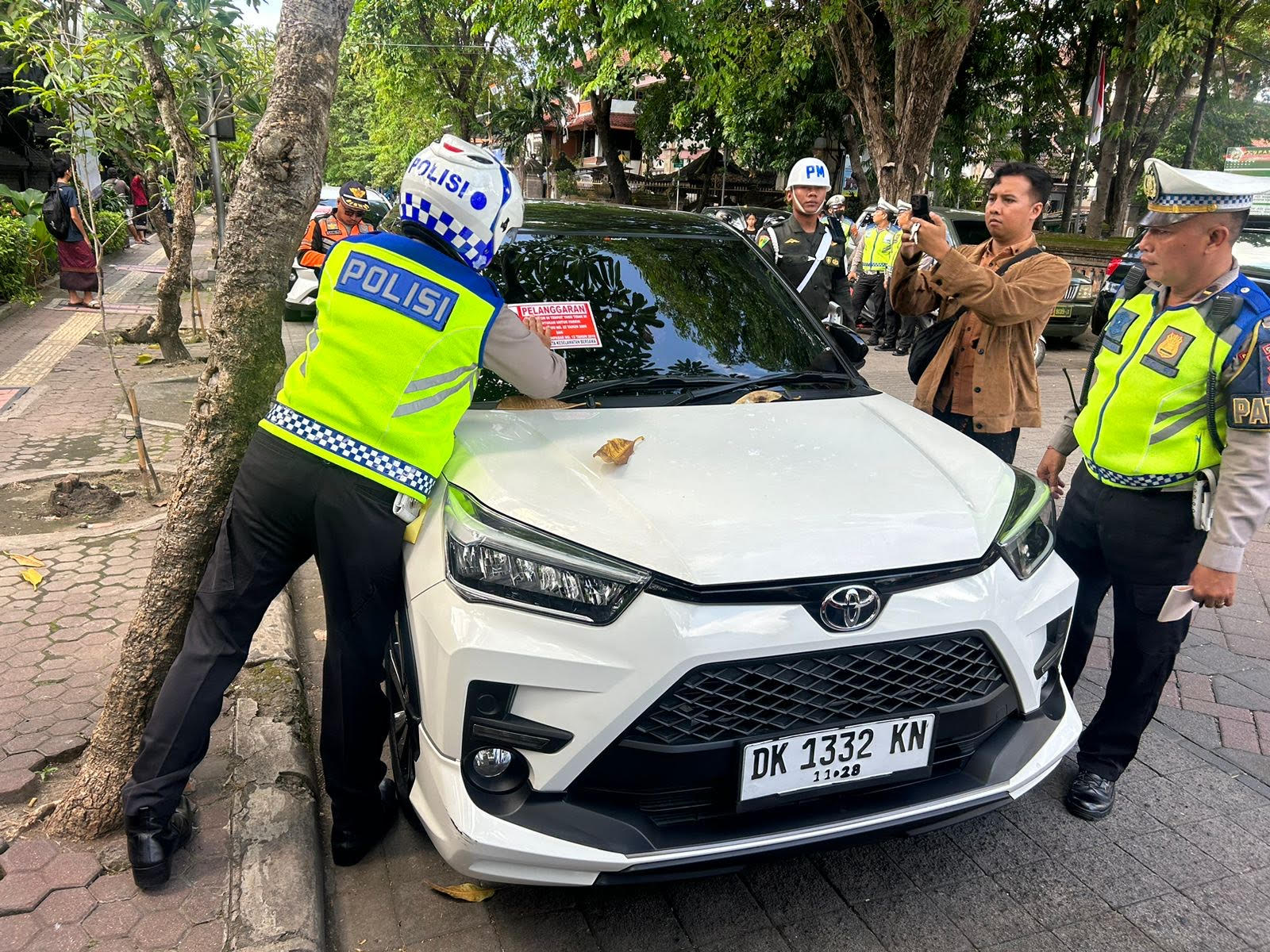 PARKIR SEMBARANGAN: Polisi memasang stiker di sebuah mobil yang melanggar parkir di kawasan jalan Kamboja Denpasar untuk memberi efek malu bagi pelaku.