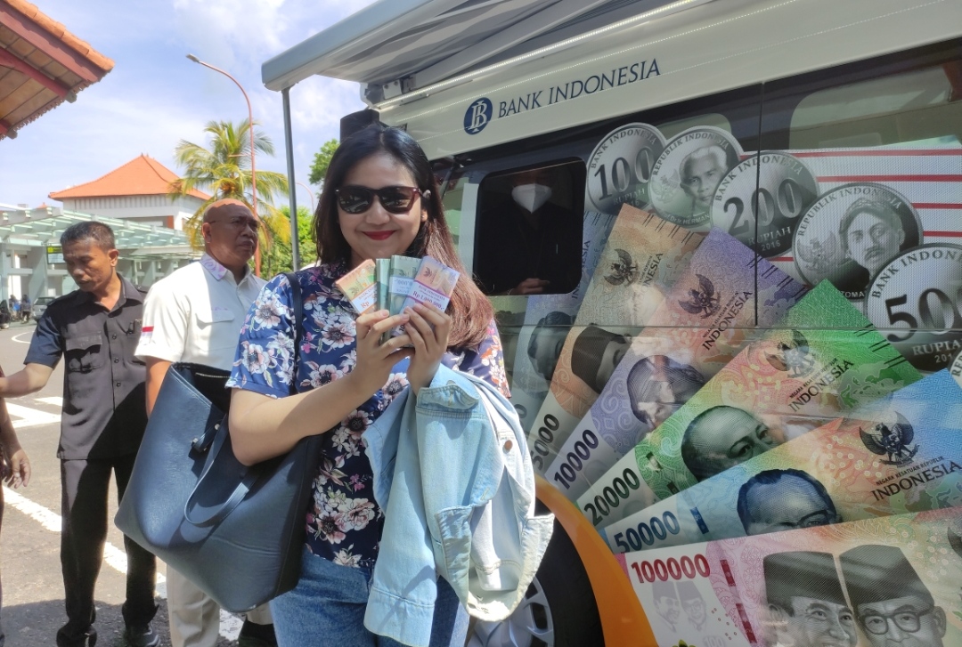 GEMBIRA: Salah seorang warga calon penumpang di Bandara I Gusti Ngurah Rai semringah setelah selesai menukarkan uang baru di kas keliling (28/3/2024).