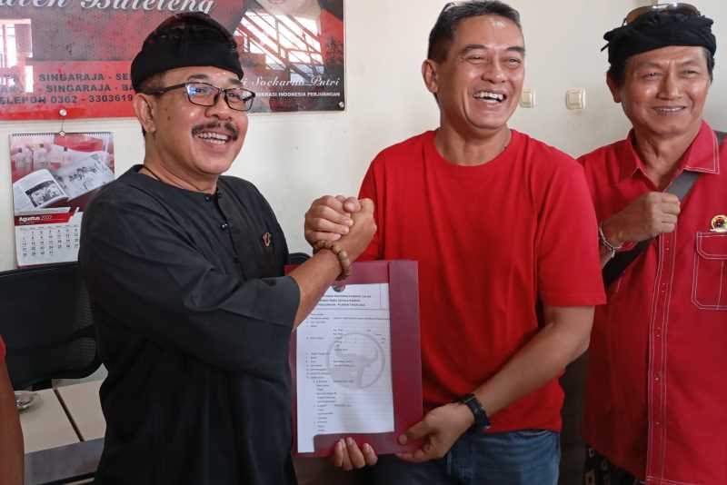 BUKTIKAN KESETIAAN: Ketut Putra Sedana (kiri) saat pengambilan formulir calon bupati. Ia meyakini tidak akan lompat pagar atau pindah partai, jika tidak mendapatkan rekomendasi.(francelino junior)