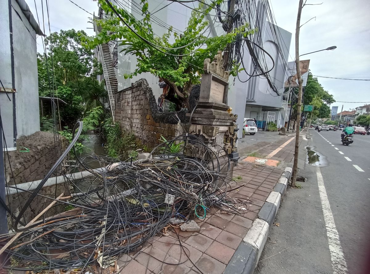 BERSERAKAN: kabel jaringan berserakan di trotoar membahayakan pengguna jalan.