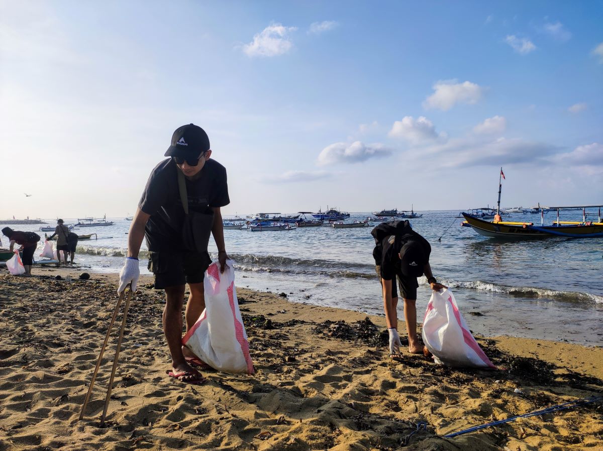 DIDUKUNG EIGER: Peserta memungut sampah pantai bertopi Eiger Adventure di pantai Sanur.