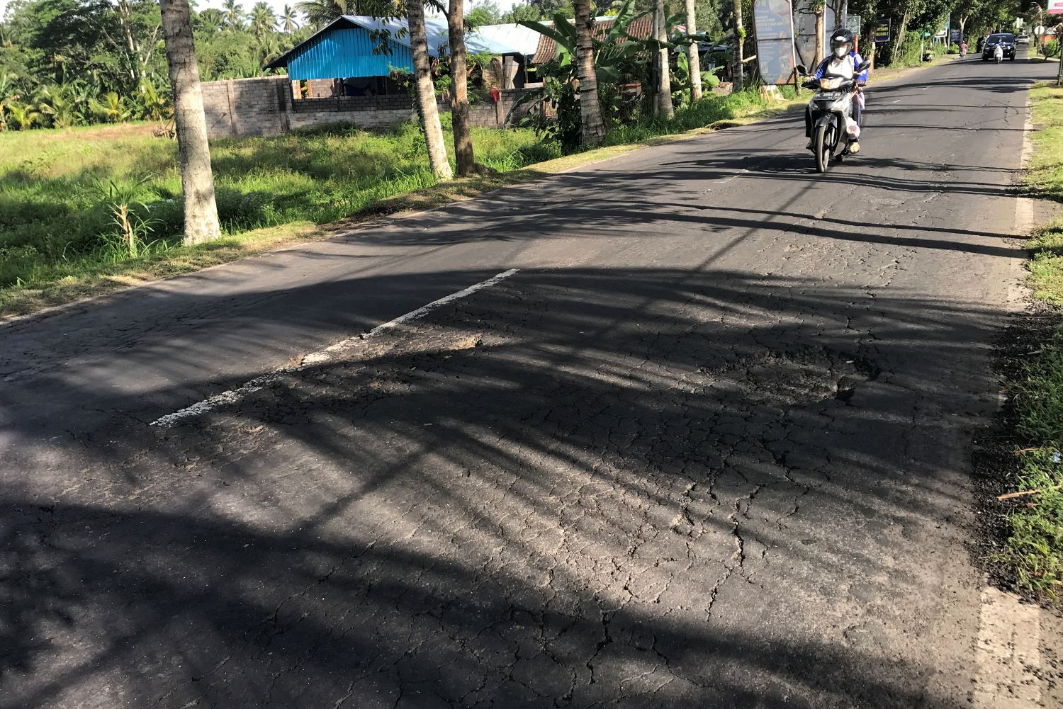 RAWAN KECELAKAAN: Kondisi jalan raya Darmasabha Petang Badung yang rusak dan belum diperbaiki