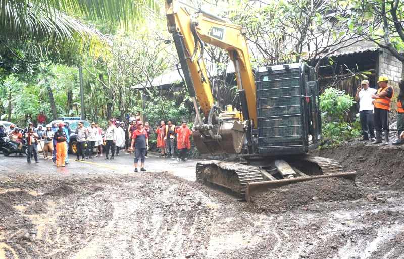BERSIHKAN MATERIAL : Proses pembersihan material pasir dan kerikil yang menutup seluruh badan jalan di Sanghyang Ambu, Desa Bugbug, akibat hujan deras. (zulfika Rahman/radar bali)
