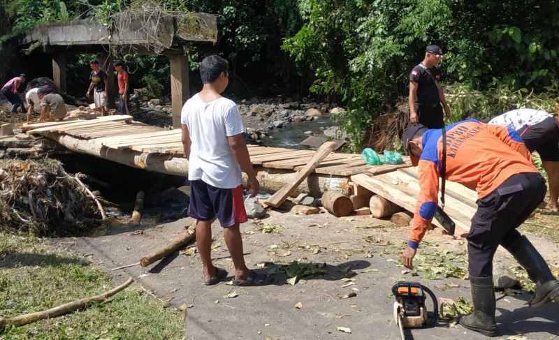 GOTONG ROYONG : Jalan rusak usai diguyur hujan, warga membangun jembatan penghubung antara Desa Belong dan Desa Yeh Poh, Karangasem. (Istimewa)