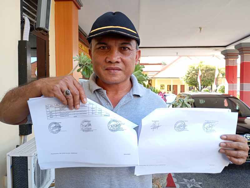 TUNJUKKAN BUKTI: Ketua Komite SDN 4 Selat, Putu Ardika menunjukkan perbedaan tanda tangan pada berkas sekolah dan mengadukan kepala dan bendahara SDN 4 Selat.(francelino junior)