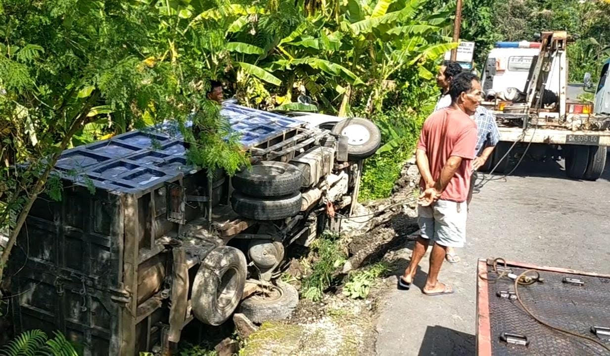NAHAS DINI HARI : Evakuasi truk pengangkut yang terguling di jalanan menurun Desa Talibeng, Sidemen akibat rem blong. (zulfika rahman/radar bali)