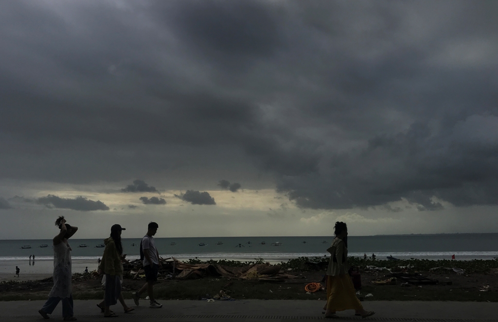 MENDUNG: Sejumlah wisatawan asing berjalan di jogging track kawasan Pantai Kuta, Kamis 4 Juli 2024.