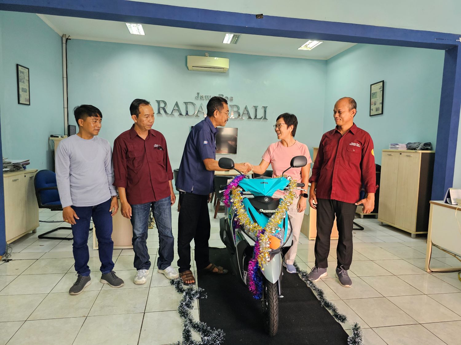 PELANGGAN SETIA: Pelanggan asal Lovina Buleleng Dewi Dwiningsih menerima hadiah sepeda motor New Yamaha Mio yang diserahkan langsung oleh Direktur Jawa Pos Radar Bali, Justin M. Herman Sabtu (6/7/2024