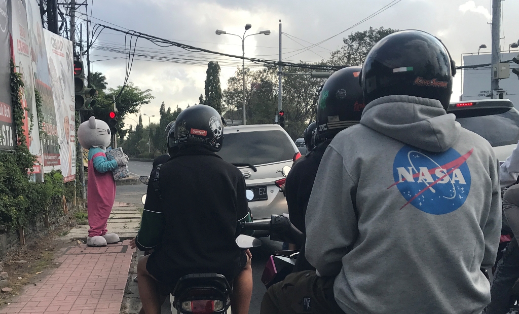 BADUT: Pengamen boneka badut sedang beraksi di perempatan jalan bypass Ngurah Rai- Pemelisan, Sesetan, Denpasar, Minggu 28 Juli 2024.