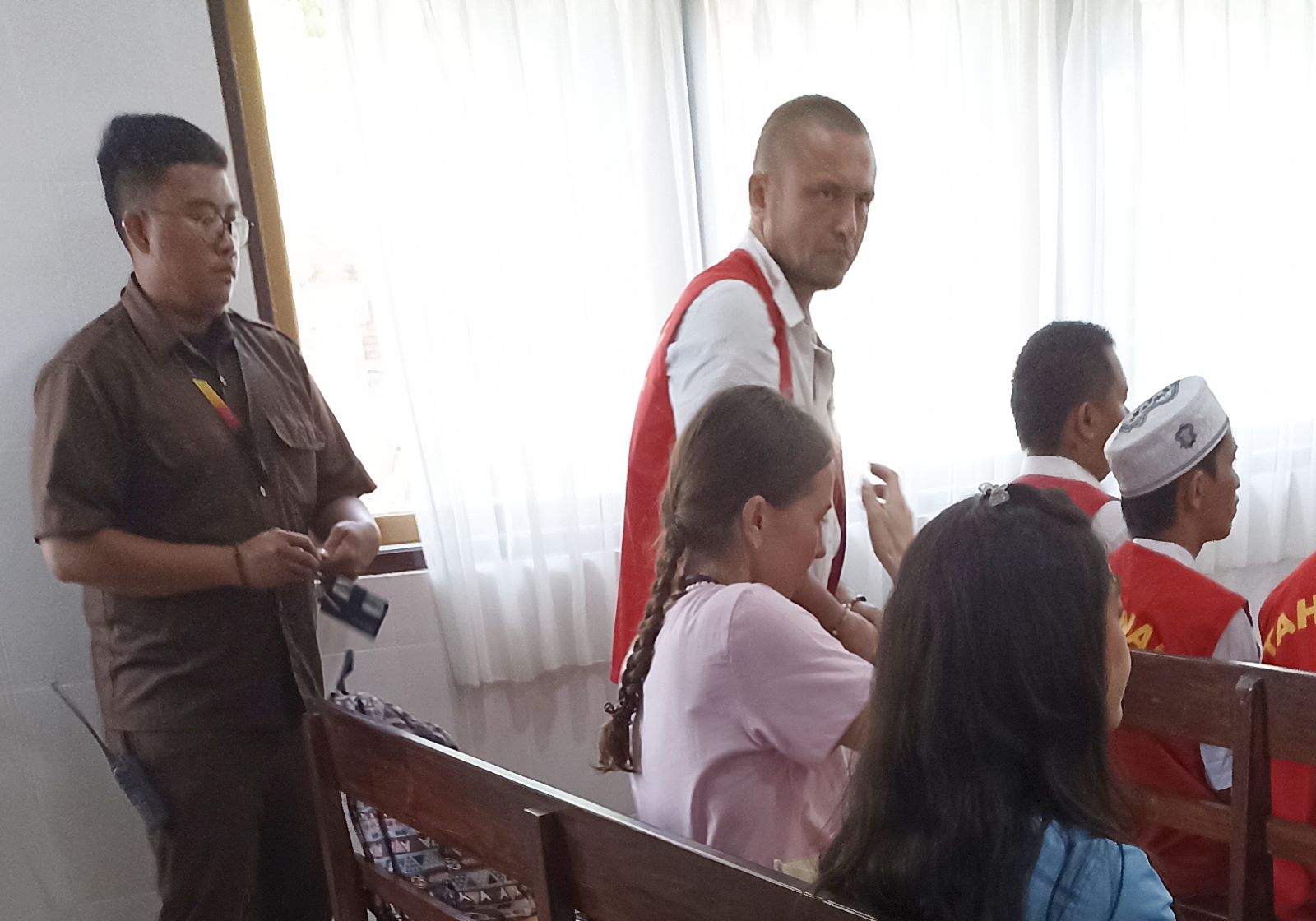 PIDANA BERAT: Terdakwa Anton Simutov (berdiri memakai rompi tahanan) dan korba duduk di kursi saksi saat sidang di PN Denpasar, Selasa 6 Agustus 2024.