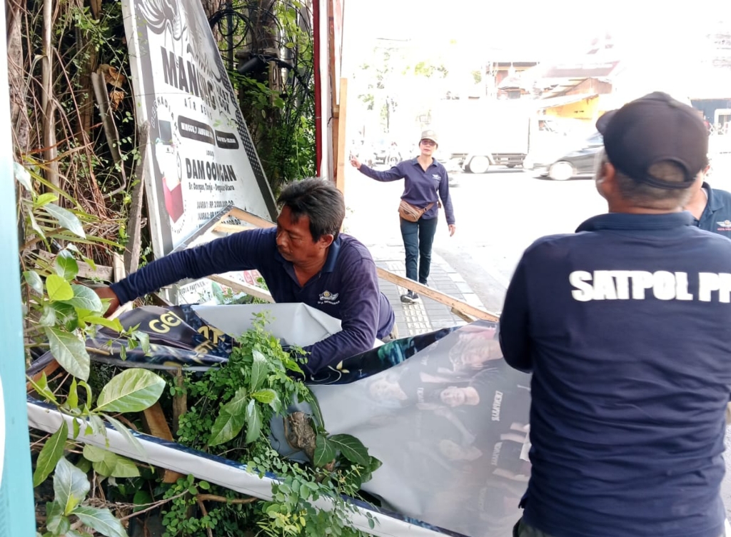 PENERTIBAN: Satpol PP Kota Denpasar saat melakukan penertiban baliho yang telah kedaluwarsa, Rabu 14 Agustus 2024.