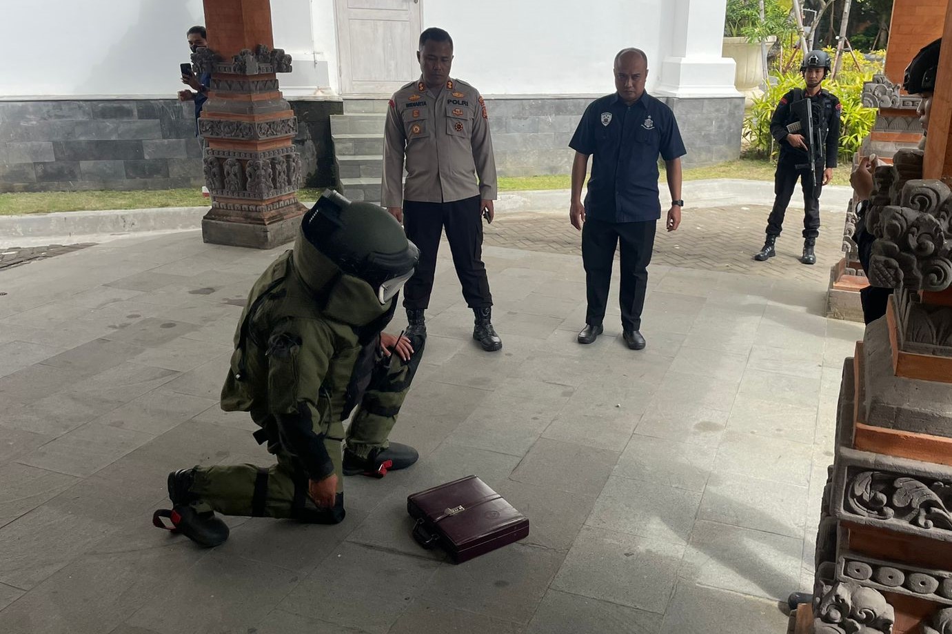 HEBOH: Personil tim oenjinak bom Polda Bali tengah memeriksa tas koper warna merah  marun yang ditemukan di area parkir VIP Bandara I Gusti Ngurah Rai, Selasa 27 Agustus 2024.