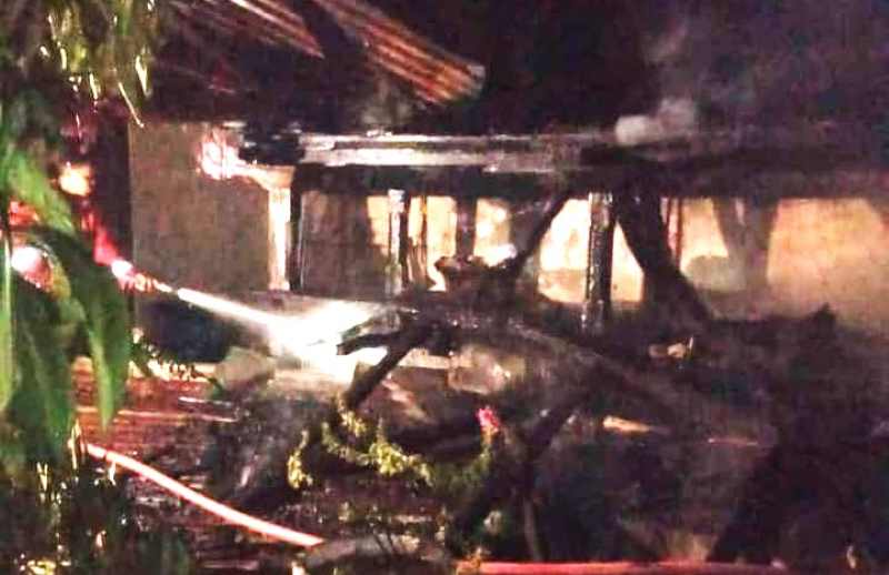 PADAMKAN API : Petugas tampak memadamkan api yang juga ikut membakar mobil yang ada di sana. Kebakaran ini diduga akibat adanya arus pendek listrik.( Foto: Polsek Kota Singaraja untuk Radar Bali)