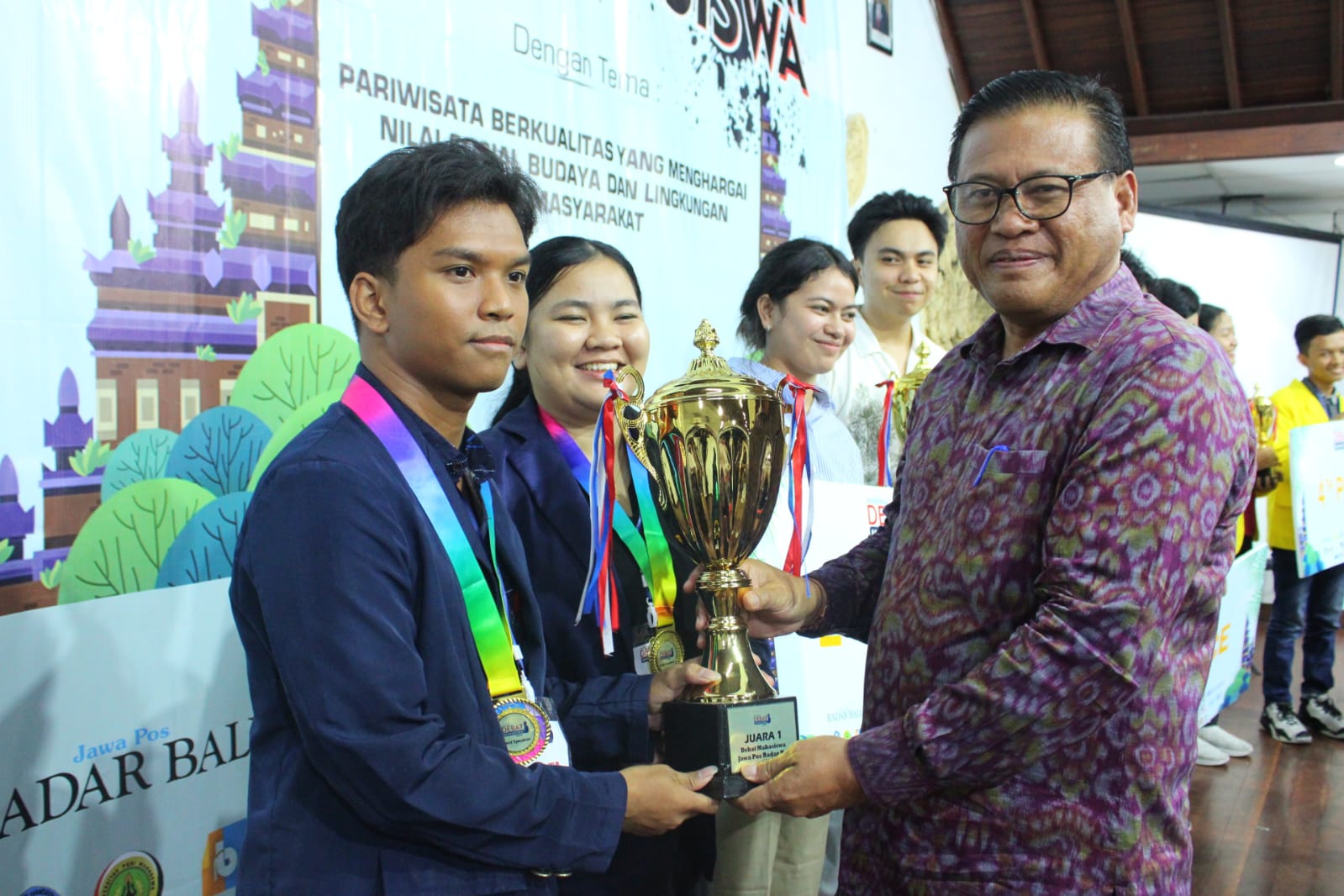 SERAHKAN TROFI: Sekda Kota Denpasar Ida Bagus Alit Wiradanadi (kanan) Aula Universitas PGRI Mahadewa Bali, Denpasar, Minggu (22/9/2024).