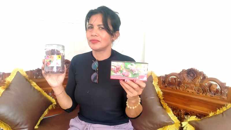 PERLIHATKAN CONTOH PRODUKSI : Pembina Gapokwatan Lumbung Rasa Desa Pitra Ni Ketut Indiani Masmini yang menunjuk hasil olahan teh bunga rosela.[juliadi/radar bali]