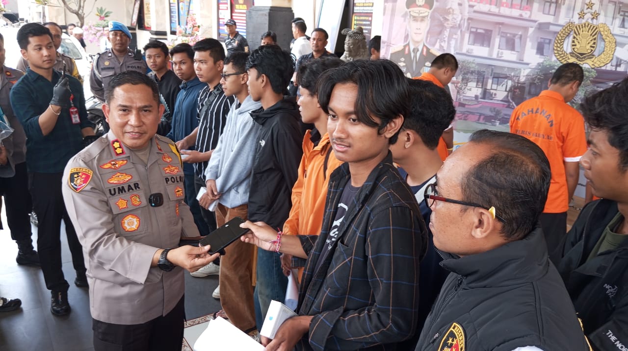 DISERAHKAN: Kapolres Gianyar AKBP Umar (kiri) memberikan Hp ke korban copet saat konser musik.