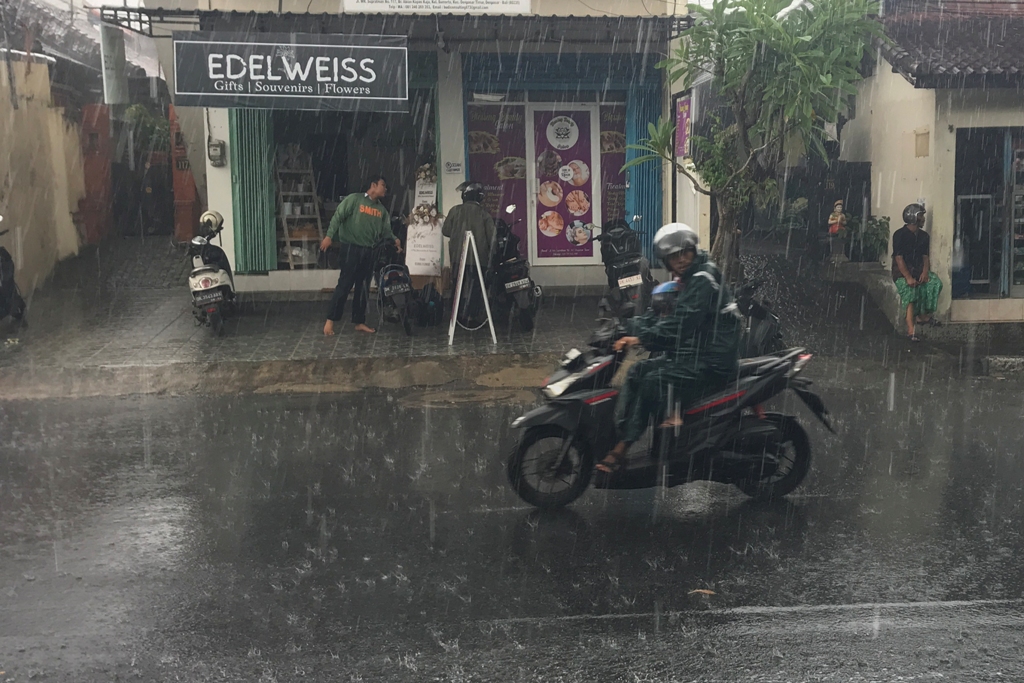 HUJAN: Hujan deras di kawasan Jalan WR Supratman, Denpasar, di mana pengendara motor terlihat melaju meski hujan turun dengan intensitas tinggi.