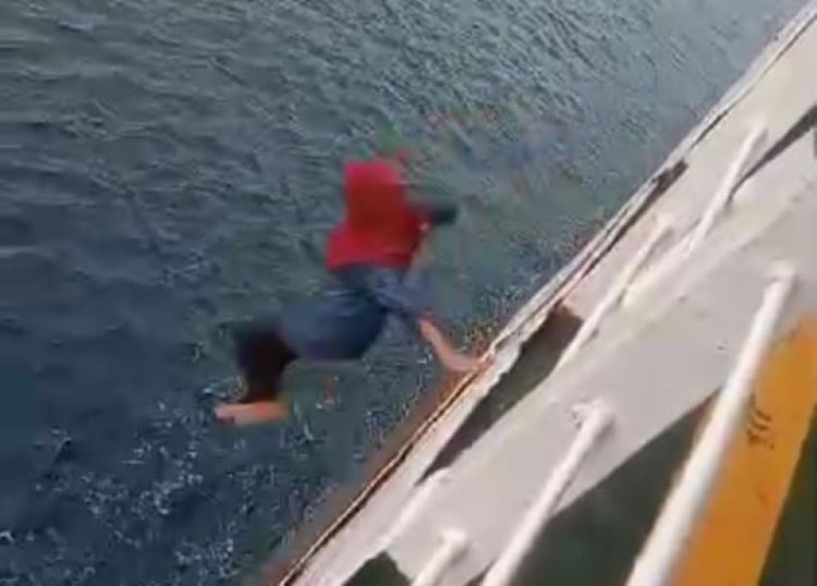 NEKAT: Wanita berhijab merah yang diketahui bernama Wayan Indriani saat loncat ke laut dari KMP Citra Mandala di Selat Bali, 21 Desember 2024.