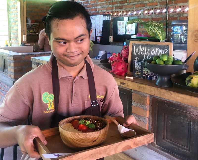 ENJOY : Pekerja Piduh Charity Cafe Bali, Gianyar, tengah mengantar pesanan menu makanan. (istimewa)