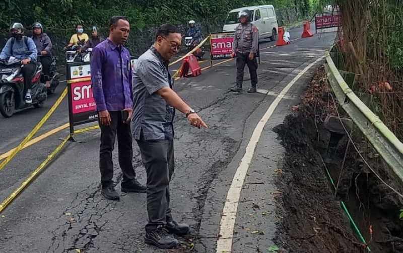 CEK KERUSAKAN : Kadis Pekerjaan Umum, Penataan Ruang, Perumahan dan Kawasan Permukiman Klungkung, I Made Jati Laksana mengecek kondisi jalan yang longsor. (Istimewa)