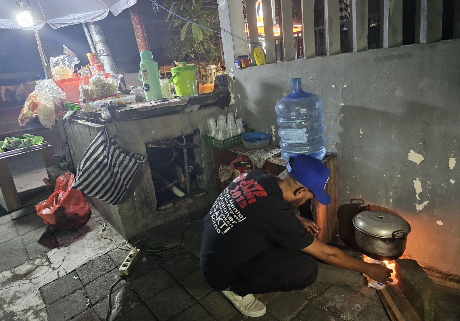 KEMBALI KE TRADISI: Romli menyalakan kayu bakar di tungku karena sudah tiga hari keliling mencari Gas LPG 3 kilogram