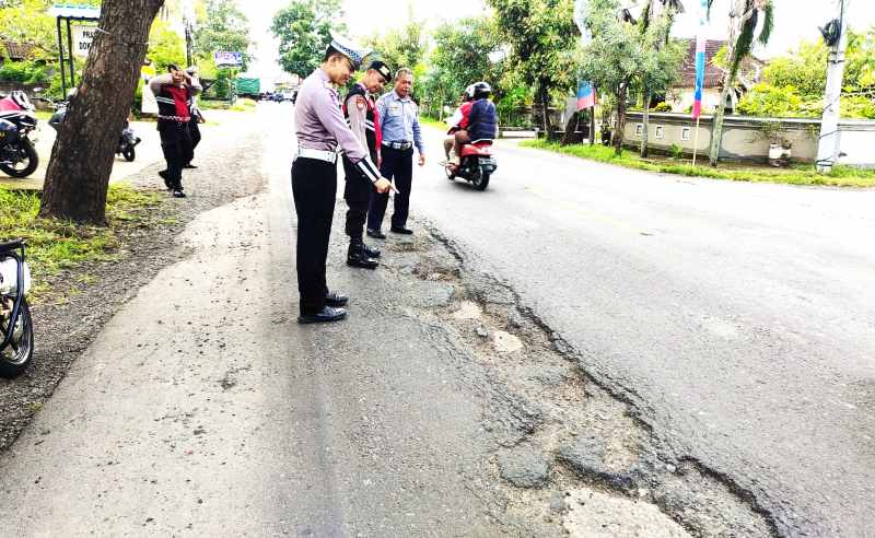PANTAU KERUSAKAN PARAH : Polisi melakukan survei jalan Denpasar - Gilimanuk yang rusak, berlubang, berisiko kecelakaan. (foto:satlantas polres jembrana)