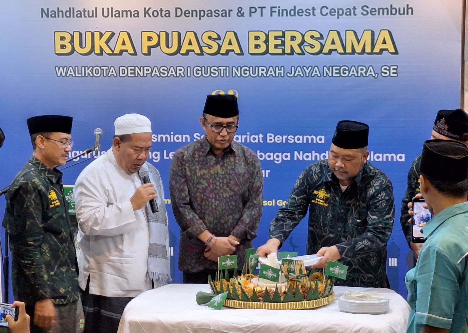 HARMONI BUKA BERSAMA: Ketua PCNU Kota Denpasar H. Moh. suryadi memotong tumpeng yang diserahkan kepada Wali Kota IGN Jaya Negara menandai peresmian Sekber PCNU Kota Denpasar Kamis, 20 Maret 2025.