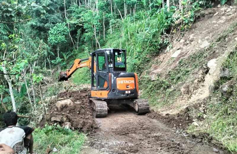 DIBERSIHKAN : Petugas saat melakukan penanganan pembersihan material longsor yang menutup akses jalan warga di Jalan lingkungan Pekarangan.(BPBD Karangasem)