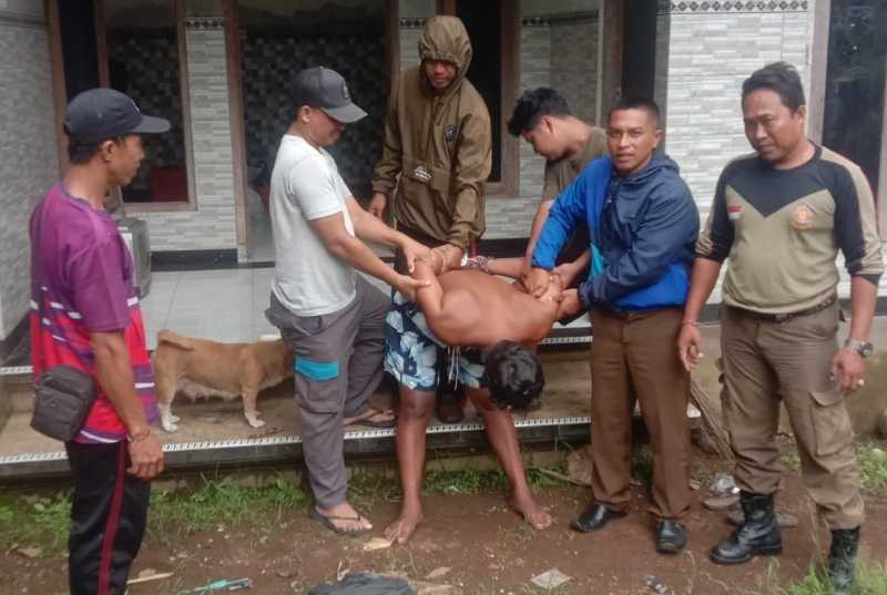 DITANGKAP : IGS saat diamankan warga dan Satpol PP karena mengamuk sembari membawa sajam.(foto: istimewa)