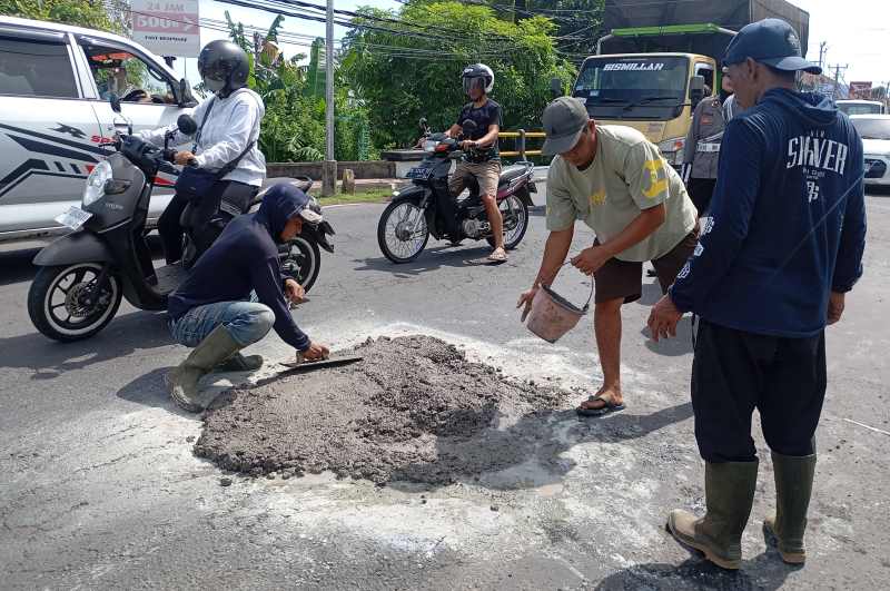 TAMBAL PAKAI SEMEN DAN PASIR: Langkah perbaikan darurat jalan yang rusak di Singaraja, Buleleng. (francelino junior)