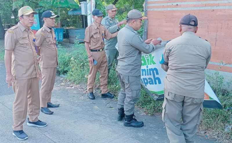 DIBERSIHKAN : Penertiban reklame di pinggir jalan depan pintu keluar Pelabuhan Gilimanuk.(foto: lurah gilimanuk)