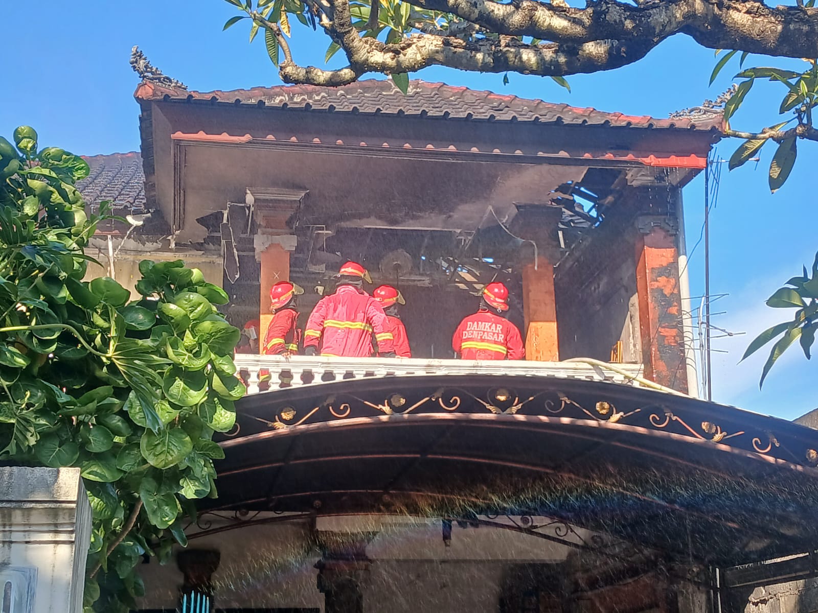 NYARIS LUDES: Tim Damkar berupaya memadamkan api di lantai dua rumah bermotif Bali Jalan Seruni No. 20, Sumerta Kauh,  Denpasar Timur, Sabtu, 10 Mei 2025.