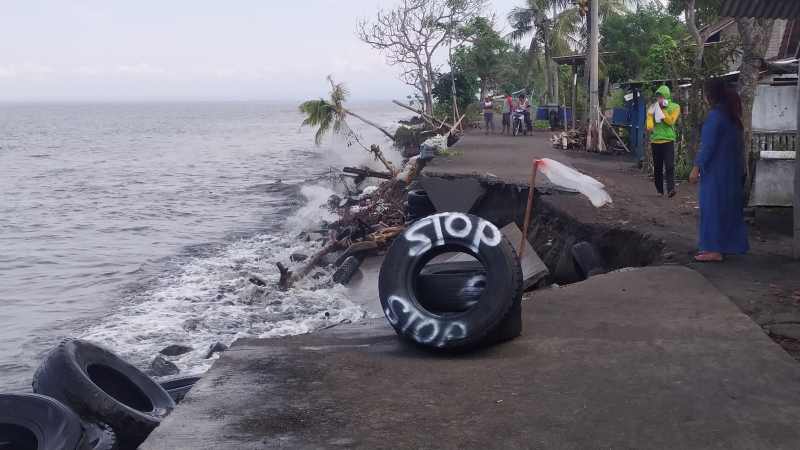 DITERJANG OMBAK BESAR : Jalan rabat beton yang putus karena ombak besar membuat bagian bawah jalan abrasi di pesisir pantai Pebuahan, Desa Banyubiru, Jembrana. (foto: m.basir/radar bali)