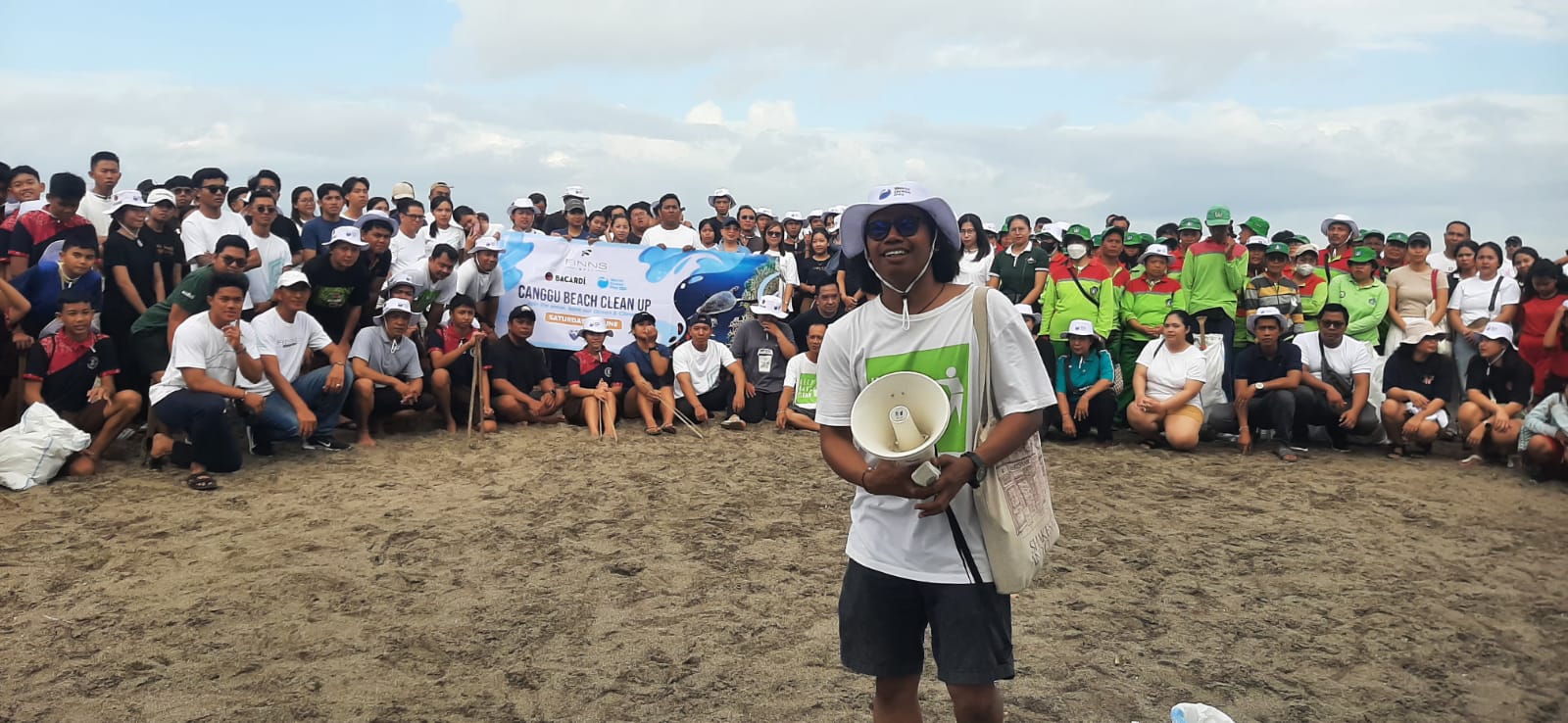 PROGRAM BERKELANJUITAN: Manaf (pegang magaphone), memimpin peserta aksi Canggu Beach Clean Up foto bersama usai mengumpulkan sampah pantai, Sabtu pagi, 7 Juni 2025.