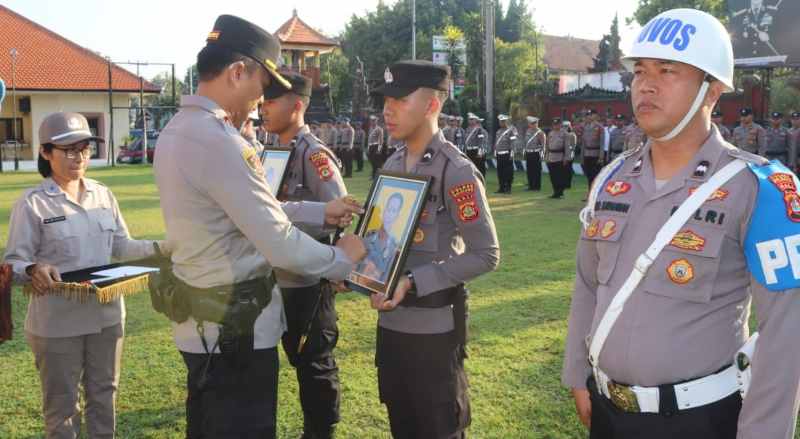 DIPECAT: Kapolres Buleleng, AKBP Ida Bagus Widwan Sutadi mencoret foto dua personelnya, sebagai simbolis resmi dipecatnya Bripka Kertayasa dan Aipda Suweta. (Foto: Polres Buleleng untuk Radar Bali)