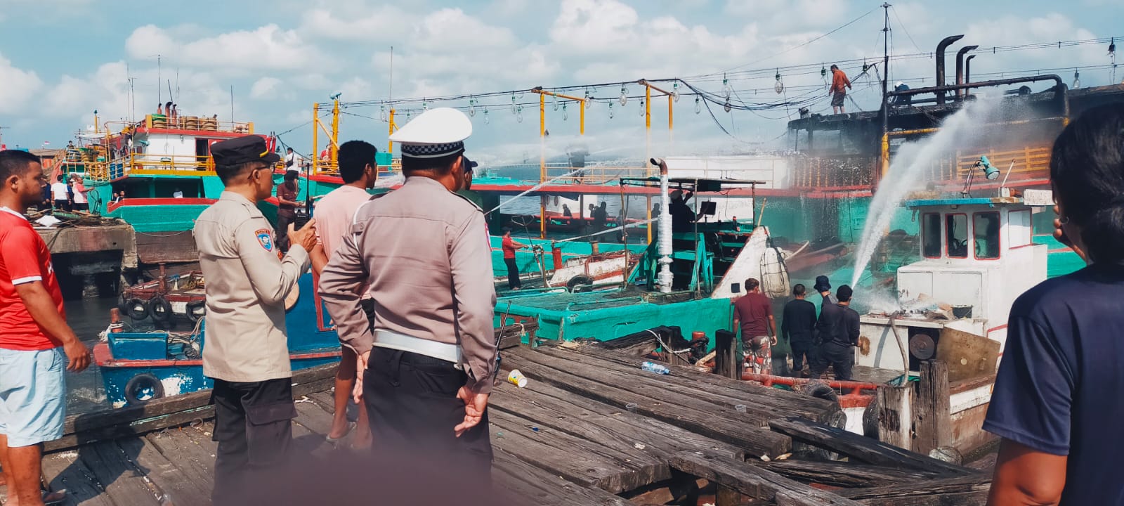 NYARIS MENYAMBAR: Petugas berupaya memadamkan api dari kapal ikan lego jangkar di Pos II Dermaga Barat Pelabuhan Benoa, pada Minggu, 22 Juni 2025
