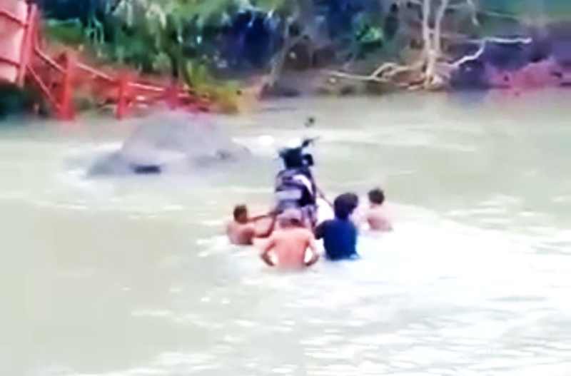 TAHUN 2025, MIRIP TAHUN 1945: Warga mengangkat motor melintasi sungai karena jembatan putus sejak 4 tahun lalu. (foto: Istimewa/kiriman warga)