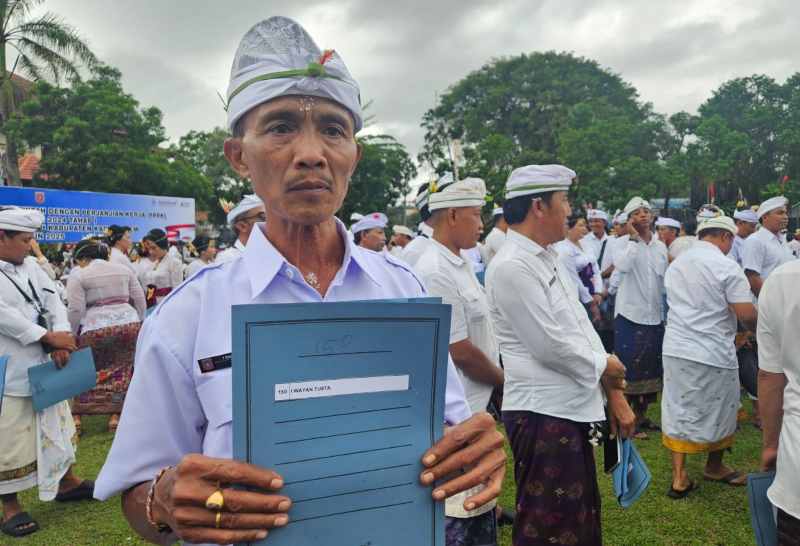 TUNJUKKAN SK : I Wayan Tusta saat menunjukkan SK PPPK usai resmi dilantik di Lapangan Tanah Aron, Amlapura. (Foto zulfika Rahman/Radar Bali)