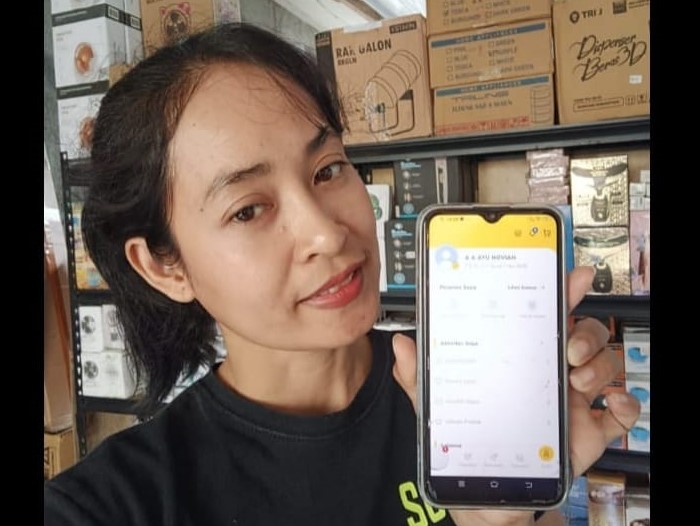 Bu Gek pemilik toko Supershop di Denpasar Barat tunjukkan akun platform kuning.