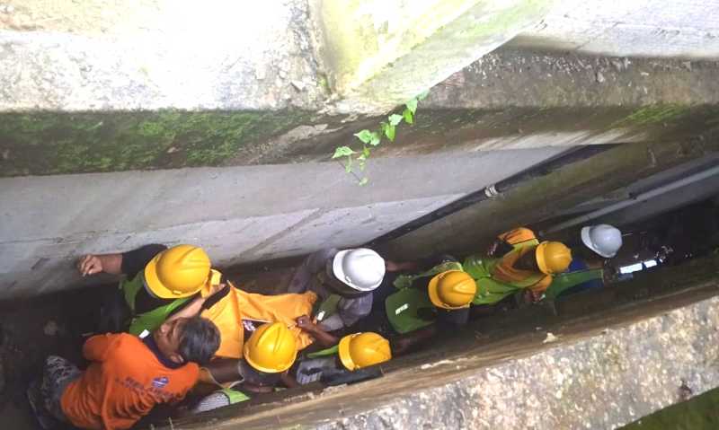 SUSAH PAYAH EVAKUASI KORBAN : Petugas mengevakuasi jenazah Sonni yang terjatuh di bawah bangunan vila yang sempit. (foto: dok. BPBD Gianyar)