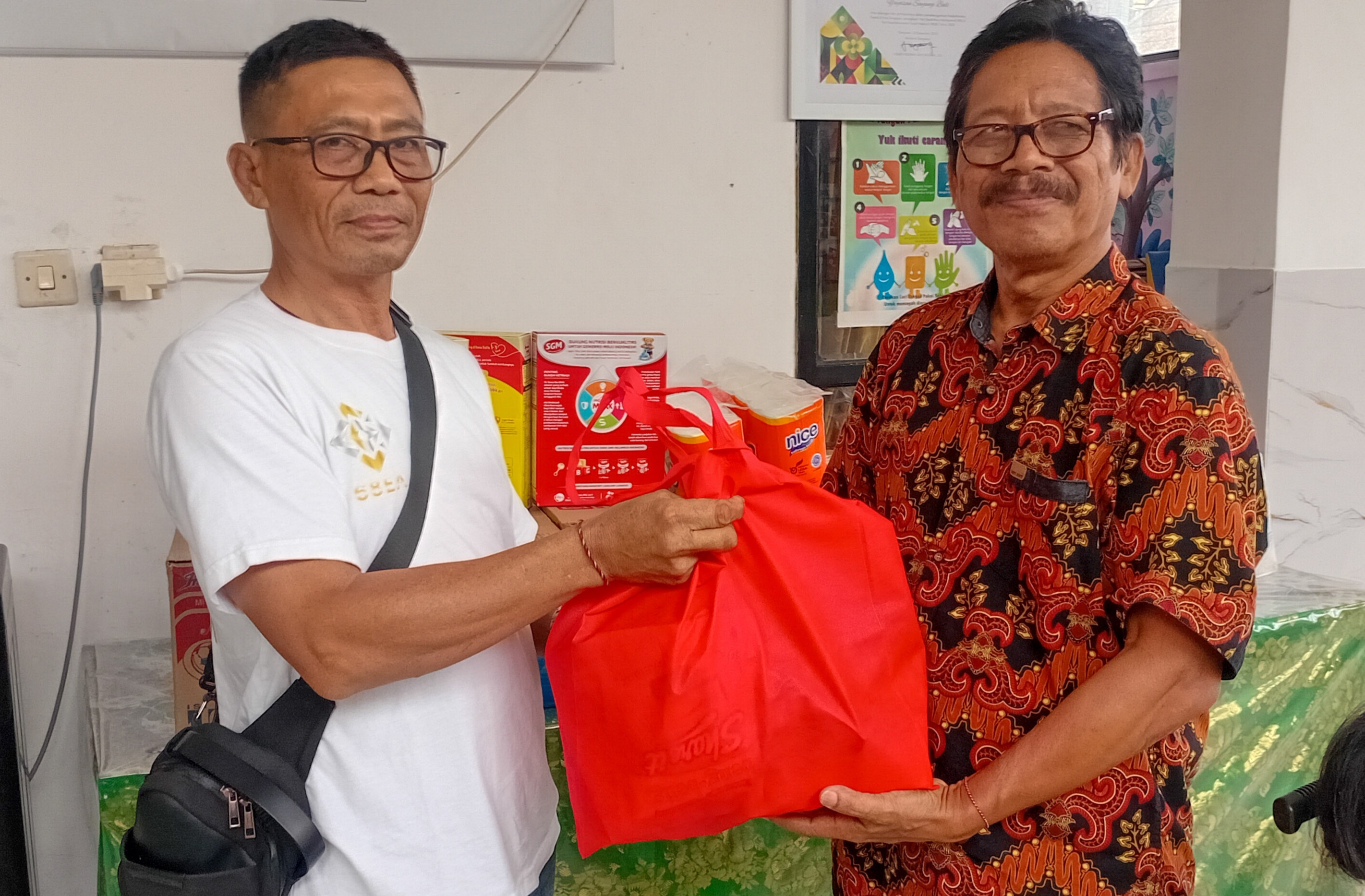 BERBAGI BAHAN POKOK: Dewa Putu Wirata (Kanan) Pimpinan Yayasan Sayangi Bali Menerima Bantuan dari Ketut Seriada, Koordinator GS Investment 68EA Bali.