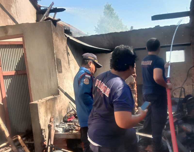 HANGUS TERBAKAR : Petugas sedang melakukan pemadaman di salah satu rumah yang terbakar. Peristiwa ini terjadi, diduga karena korsleting listrik. (Foto: Polres Buleleng untuk Radar Bali)