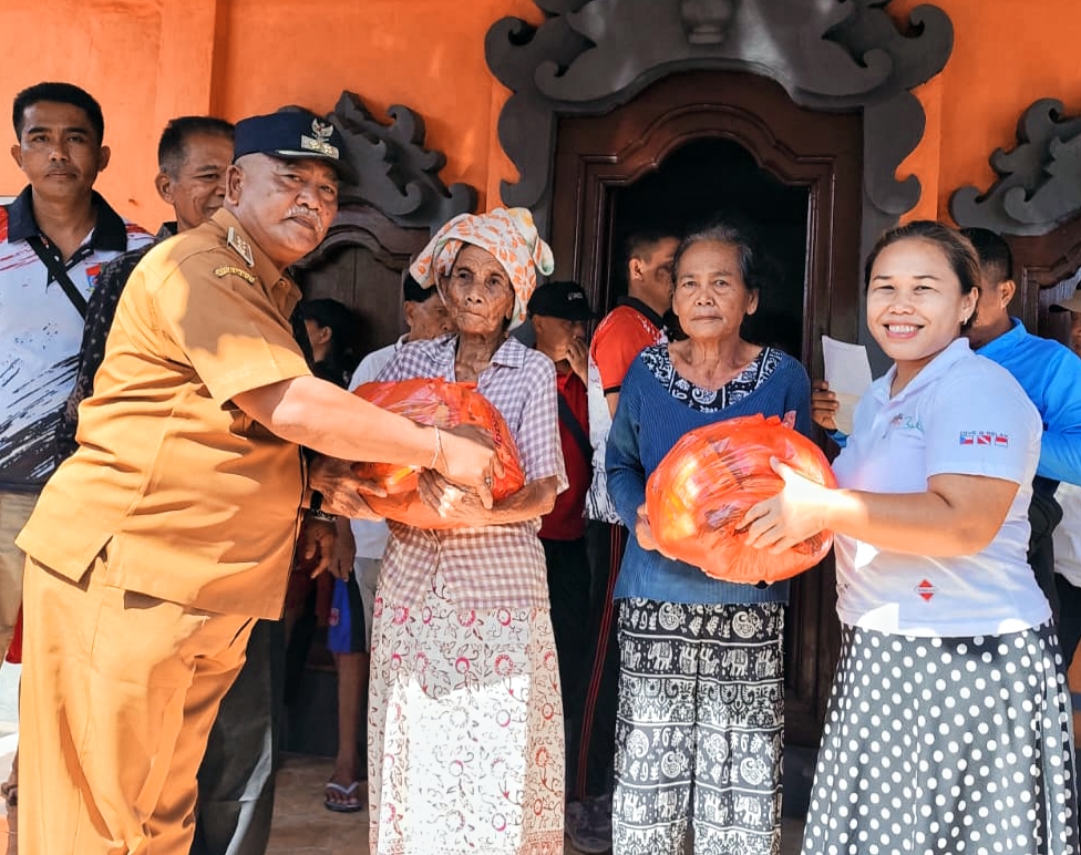 Perbekel Kubu I Gede Putu Ngurah Astawa (kiri) menyerahkan bantuan dalam bakti sosial dan tali kasih peduli sesama (4/8/2025).