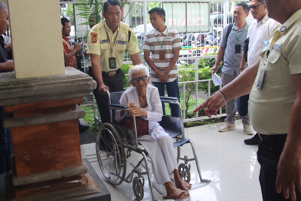 BEBAS DARI TUNTUTAN: Ni Nyoman Reja, 93, menggunakan kursi roda saat menjalani sidang di PN Denpasar.