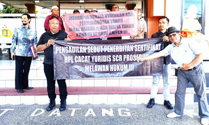 BENTANGKAN SPANDUK:  Massa Batu Ampar membentangkan spanduk dukungan, sebelum gelar umum perkara dilakukan Polres Buleleng.(Francelino junior)