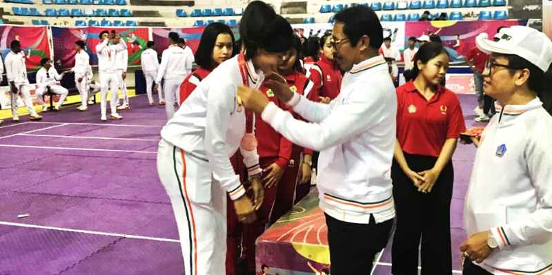 DOMINAN: Made Sutama mengalungkan medali untuk atlet Kabaddi di GOR Lila Bhuana . (Foto KONI Badung untuk Radar Bali )