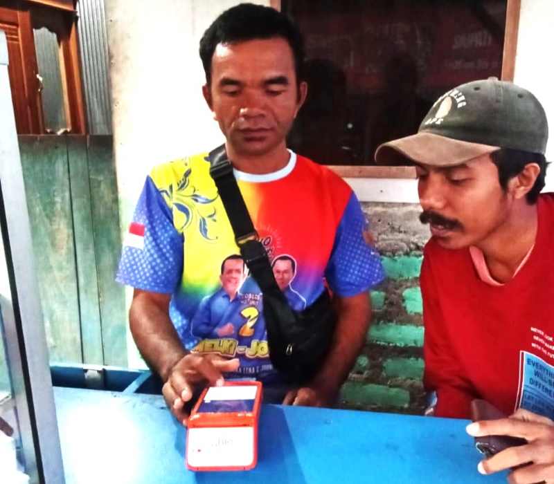 BANTU WARGA DI PELOSOK DESA NTT : Kaderi (kiri) melayani seorang masyarakat yang akan melakukan transaksi. ( Foto Marsellus Pampur)