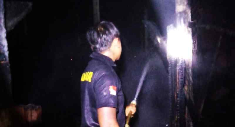 SUDAH HANGUS : Petugas semprotkan air ke kandang ayam yang hangus terbakar. (istimewa)
