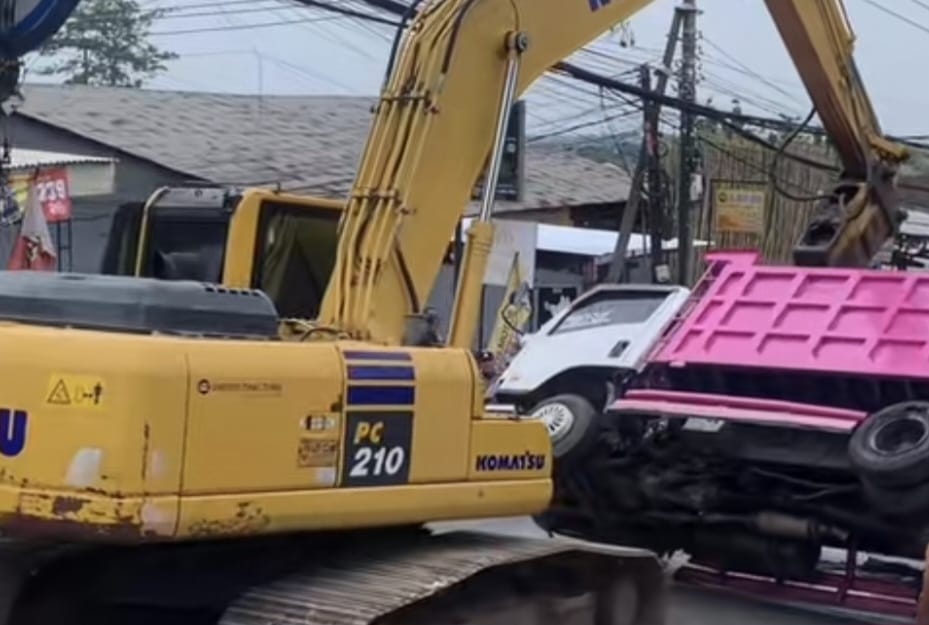 Truk warna putih kombinasi pink yang tergulung di tanjakan depan GWK